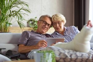 Senior couple - the man has a cast on his foot, propped up on a pillow