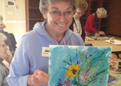 Female resident of Park Place of Elmhurst proudly displaying a painting she created