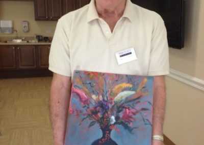 Male resident of Park Place of Elmhurst proudly displaying a painting she created