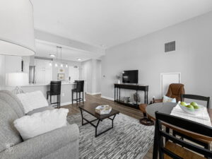 View of a bright open-concept senior apartment with a living area, TV, and dining table.