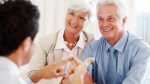 Portrait of a cheerful old couple discussing financial matter with advisor at office